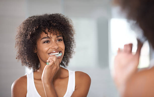 a woman brushing her teeth in front of a mirror