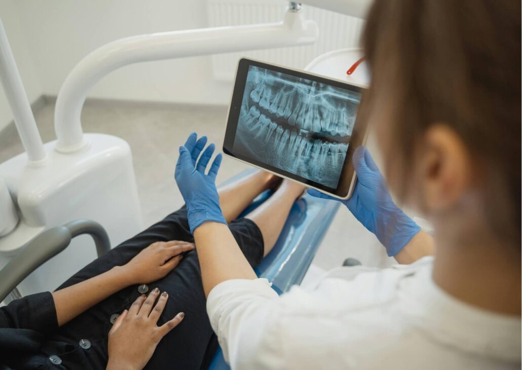 Dentist reviewing a dental X-ray with a patient to diagnose the source of pain and evaluate a suspected cracked tooth.