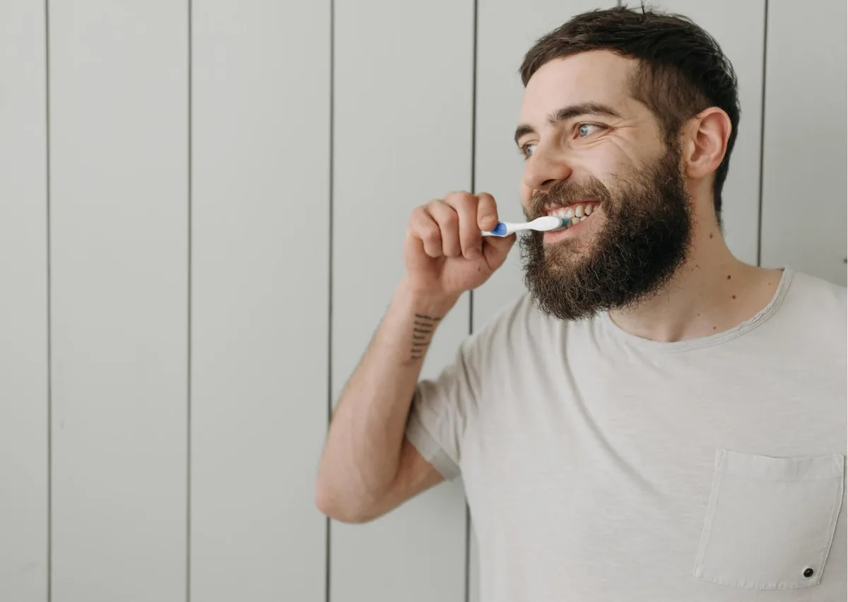 Man brushing his teeth to maintain his smile and care for teeth after dental bonding.