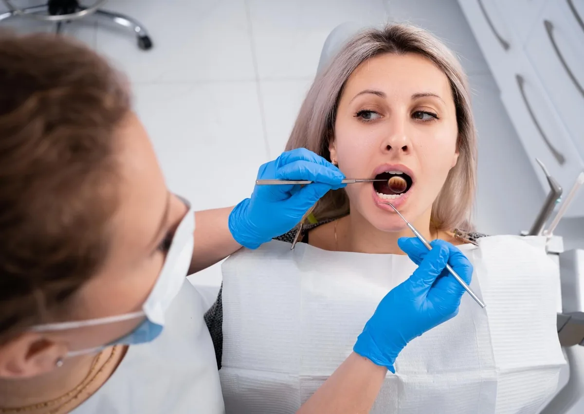 Dentist examining a patient’s mouth for a persistent canker sore that has not healed.